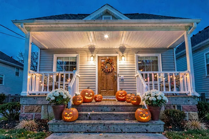 Halloween porch at blue hour, carved pumpkins on the steps — example output